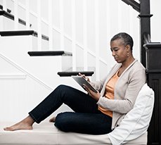 woman sitting on stairs looking at North Trust on a tablet